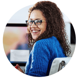 Woman sitting at computer looking over her shoulder smiling