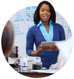 k-12 teacher at a whiteboard, using PowerSchool's as a single source of record on her tablet
